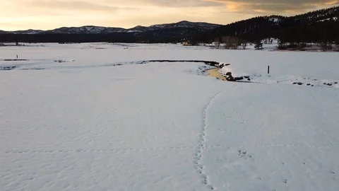 Overhead dolly to crane shot over open field covered in snow with winding cre Stock Footage 125384608