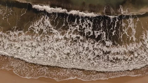 Overhead drone footage of a powerful wave breaking across a sandy beach on Stock Footage 340927990