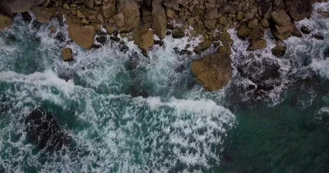 Overhead drone shot of Ocean waves on the beach hitting the rocks Stock Footage