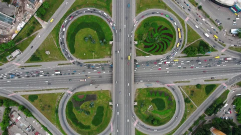 Overhead drone shot of traffic driving over roundabout with highway tunnel Stock Footage 135544418