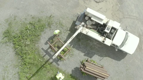 Overhead drone shot of utility workers moving pipes with a crane truck Stock Footage 137498694