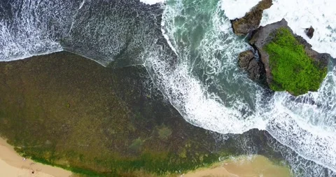 Overhead drone shot of wave on the beach crashing coral rock Stock Footage 224411357