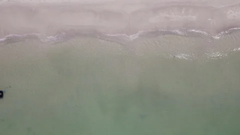 Overhead drone shot of waves crashing near shallow tropical beach shoreline Stock Footage 334870032