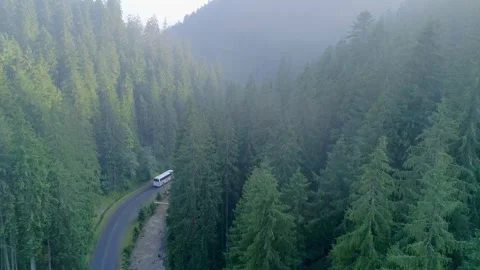 Overhead drone shot of white bus cruising serpentine Stock Footage 327551599