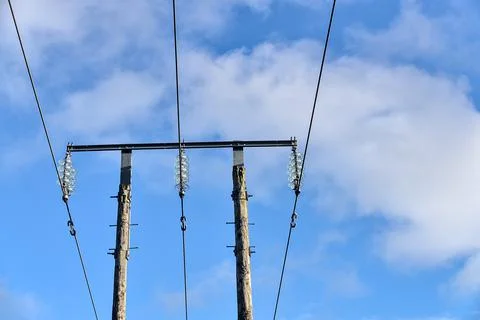 Overhead electrical power lines on old wooden pillar against the blue sky Stock Photos