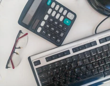 An overhead flat lay of a busy office desk featuring a computer keyboard, cal 写真素材