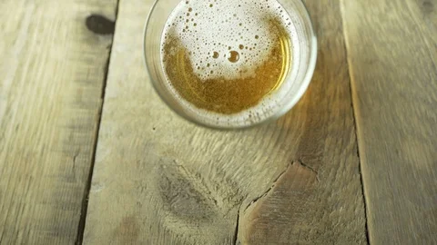 Overhead flat lay of pouring a fresh glass of lager beer on a wooden table. Stock Footage 95154428
