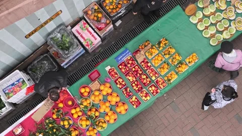 Overhead fruit stand, with shopkeeper arranging fruit, and selling orange Stock Footage 252956222