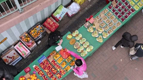 Overhead fruit stand, with shopkeeper arranging fruit, and selling orange 스톡 동영상 252956443