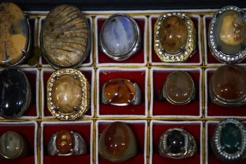 Overhead full frame display of colorful gemstone rings on red velvet grid Foto stock
