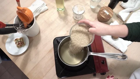 Overhead hand held shot of raw quinoa being added to pot Video stock 113495200