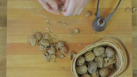 Overhead hands crack walnuts on cutting board using metal nutcracker in home Stock-Footage 333874987