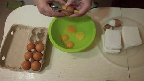 Overhead hands cracking eggs into green mixing bowl Stock Footage 342361564