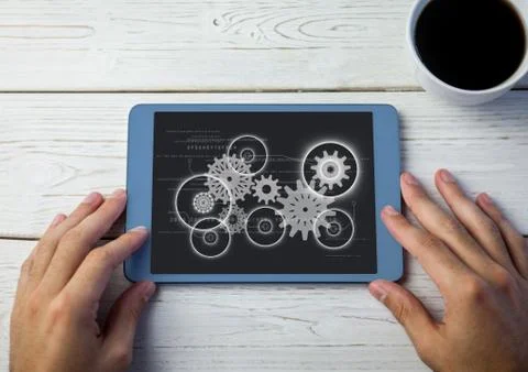 Overhead of hands with tablet and tea and white cog graphics Stockfoto's
