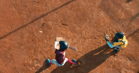 OVERHEAD Kid boy batter baseball player hits a ball over a home plate Stock Footage