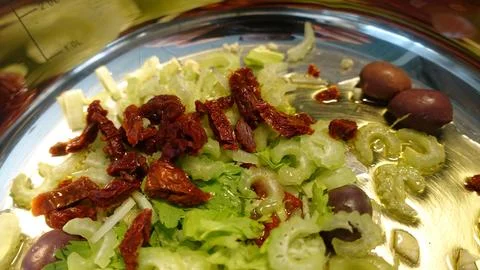 Overhead kitchen shot of sliced celery, sun-dried tomatoes and Kalamata olive Stock Photos