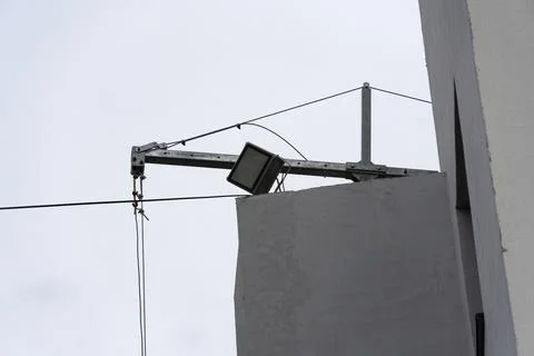Overhead light fixture is mounted on a cable stretching across a building, .. Stock Photos