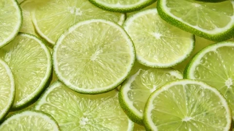 Overhead lime slices rotate in a horizontal frame, showing fresh citrus texture Stock Footage 346672306