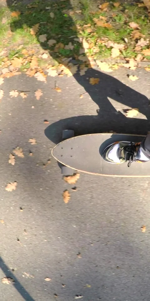 Overhead longboard ride on leafy paved path during autumn with riders Stock Footage 347964159
