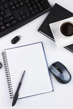 Overhead of office table with computer keyboard, mouse, USB, notepad, coffee mug Stock Photos