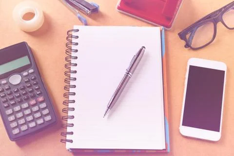 Overhead of office table with notebook, pen, mobile phone , calculator, eye.. Stock Photos