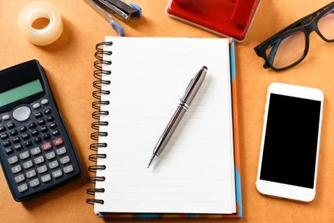 Overhead of office table with notebook, pen, mobile phone , calculator, eye.. Stock Photos