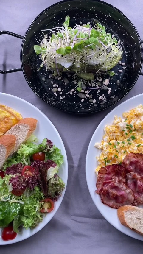 Overhead plated breakfast spread showing avocado toast skillet and scrambled Stock Footage 341626677