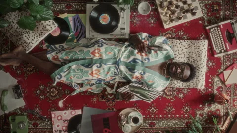 Overhead Portrait of Happy Man Lying on Retro Rug and Listening to Vinyl Music Vídeo Stock 339851262