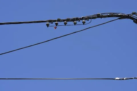 Overhead power cables and electrical connections against a blue sky Stock Photos