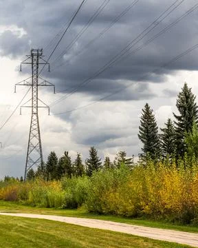 Overhead power line tower with dramatic rain cloud background Stock Photos