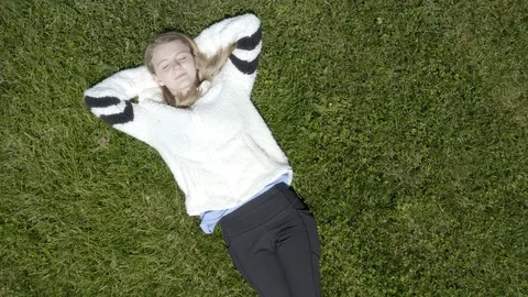 Overhead pull away shot of young girl in grass 4k Video stock 107853467
