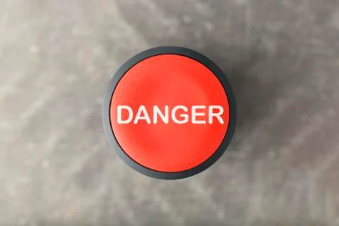 Overhead of Red 'Danger' Push Button Over Blurred Gray Background Stock Photos