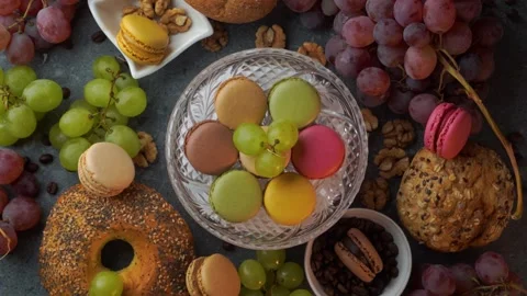 Overhead rotating glass plate of macarons with red grapes buns coffee beans.. Stock Footage 319967169