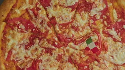 Overhead rotating shot of hot cheese pizza with Italian flag toothpick. Stock Footage 323521788