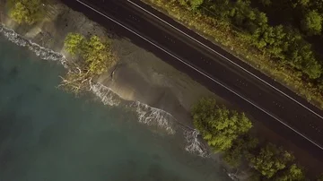 Overhead Rotating View Of A Coastal Road And Waves Crashing On A Beach Video stock 86038973