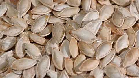 Overhead rotation of raw pumpkin seeds on wood, organic texture, healthy Stock Footage 325119224