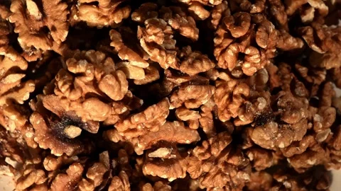 Overhead rotation of walnut kernels halves on dark surface, organic brain-like Stock Footage 325222310