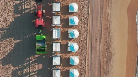 Overhead shot of a beach being cleaned by a tractor at sunrise, with paraso.. Stock-Footage 283723454