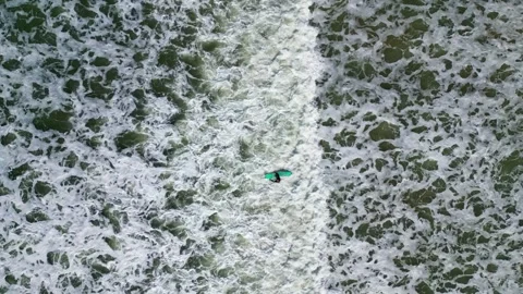 Overhead shot of big foam waves rolling on beach. Male surfer surfing in sea. Stock Footage 253793809