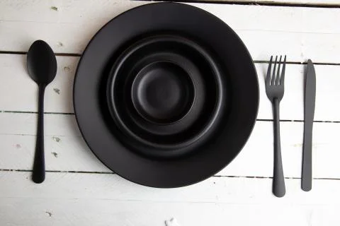 Overhead shot of black empty dining utensils on a wooden table Stock Photos
