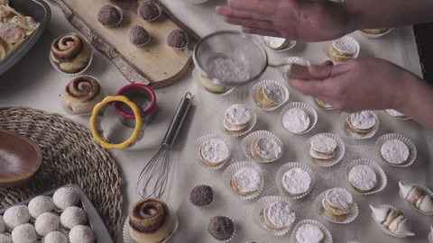 Overhead shot on confectioner's work table, hand sifting sugar into leaf alfajor Stock Footage 240354337