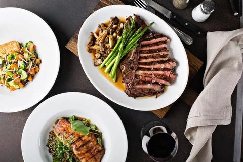 Overhead shot of a dinner table with steak and salmon Stock Photos