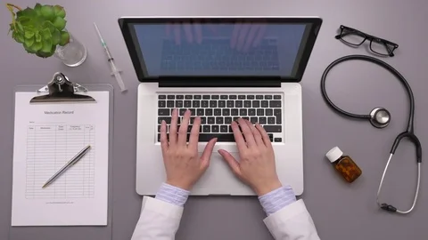 Overhead Shot Of Doctor Using Laptop While Writing On Report Stock Footage 79649988