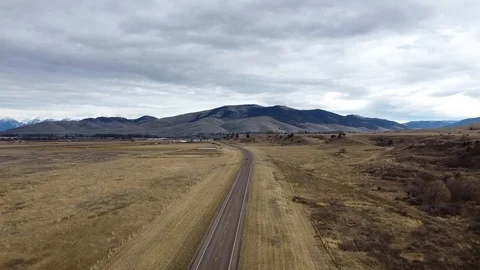 Overhead shot down a highway surrounded by large grass fields with rolling hi Vídeos de archivo 125050665