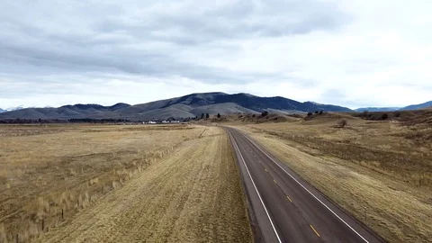 Overhead shot down a rural highway toward tree covered rolling hills with car Stock Footage 125054119