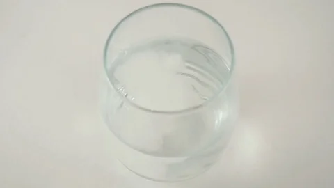 Overhead Shot of an Effervescent Tablet Falling into a Glass of Water Stock Footage 74608536