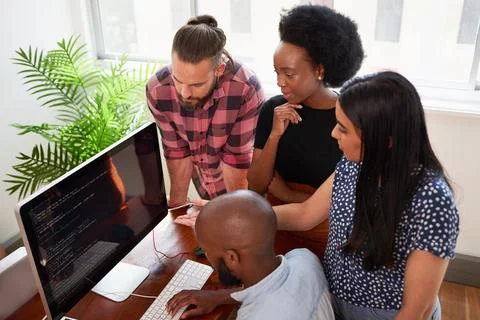 Overhead shot of four developers working together, reviewing code on big screen Stock Photos