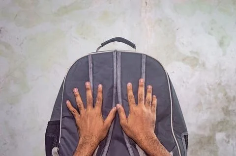 Overhead shot of a gray backpack with a man hands placed on it against a te.. Foto stock