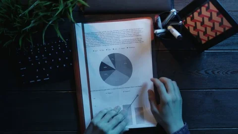 Overhead shot of man looking for contract among papers with diagrams and graphs Stock Footage 81183657