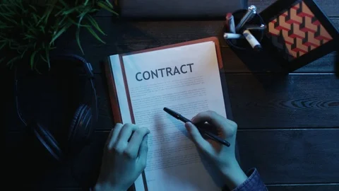 Overhead shot of man reading contract and putting on headphones for listening to Stock Footage 81184316